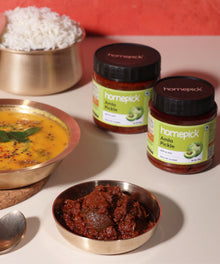 Homepick Amla Pickle jars with a bowl of rice and a dish of pickle on a light surface.